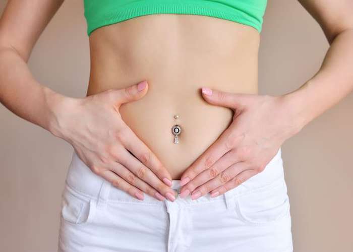 Woman putting her hands on her stomach, suffering from digestion problems including bloating and constipation.
