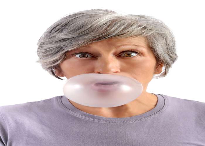 Chew gum for Alzheimer: a middle age woman chewing gum and blowing a bubble balloon.