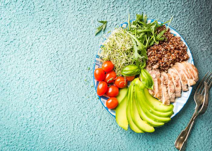 Healthy eating for Alzheimer: healthy foods on a plate including avocado, tomatoes, chicken, and vegetables.