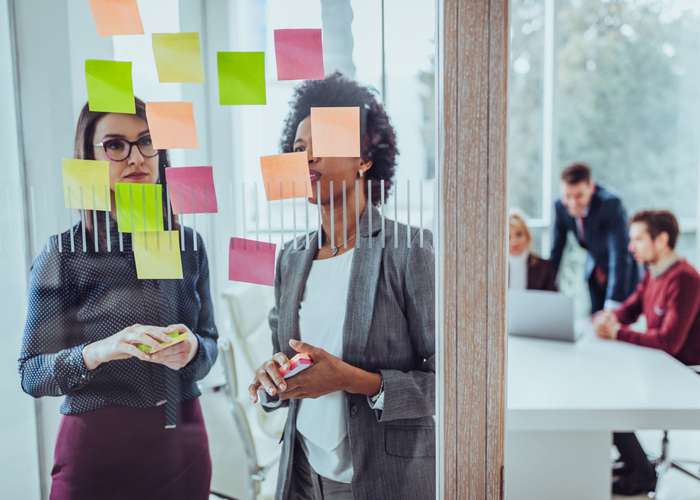 Take things at a time for ADHD: Woman looking at so many tasks created, written on post it notes, stick on the glass.