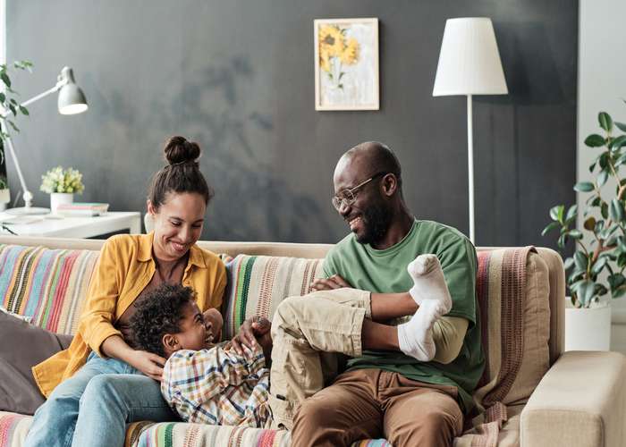 Manage your child behavior for ADHD: parents spending quality time with their kid, all sitting happy on the couch.