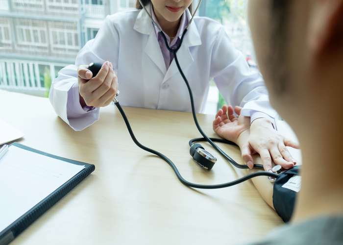 Monitor blood pressure regularly for heart disease: doctor taking a patient blood pressure in clinic.