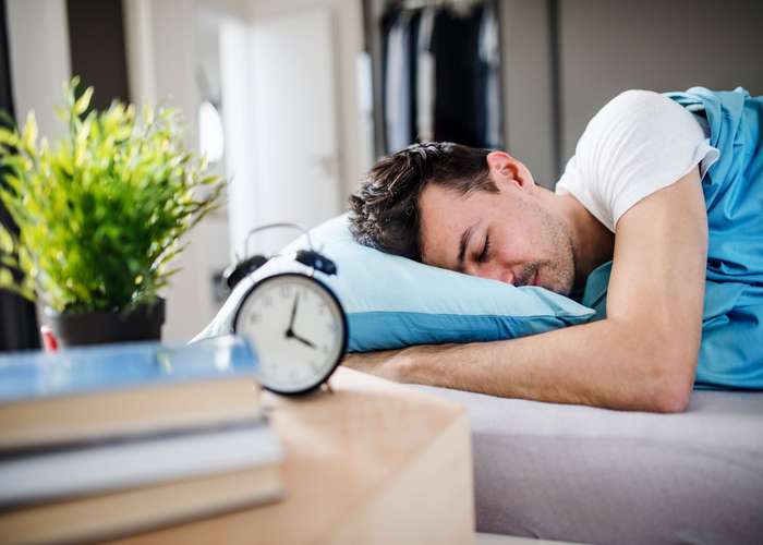 Get enough sleep to protect your heart arteries: man sleeping in bed.
