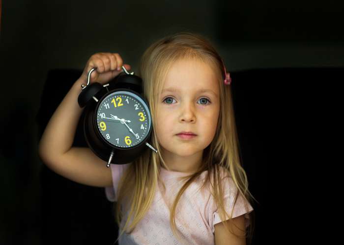 Keep track of time: little girl holding an alarm clock.
