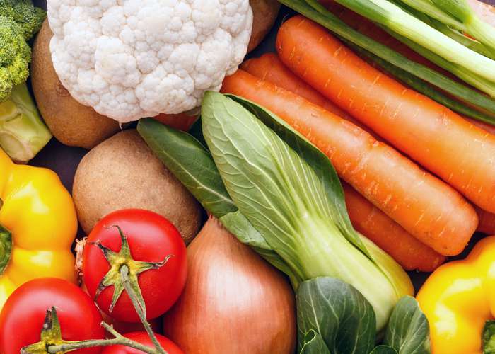 Selection of organic foods including tomatoes, cabbage, yellow pepper, carrots, onions, and potatoes.