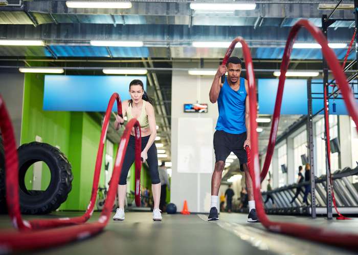 Exercise regularly for IBS: man and woman training at the gym.