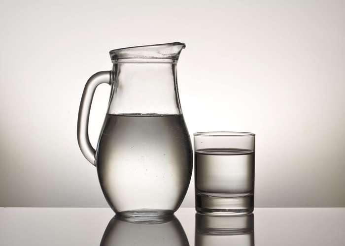 Drink lot of water for IBS: water in a glass jar and next to it a glass of water.
