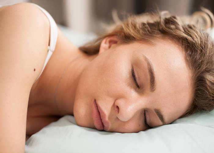 Proper sleep helps reduce stress and anxiety: young woman in deep sleep with head on the pillow