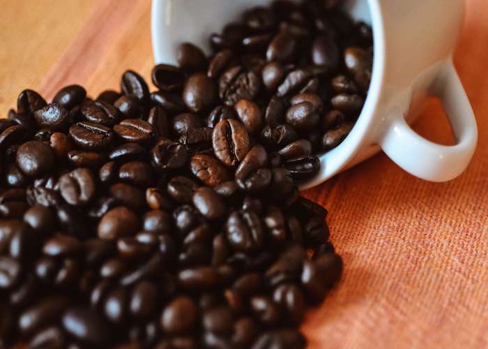 Limit caffeine for Alzheimer: cup of coffee filled with roasted coffee beans.