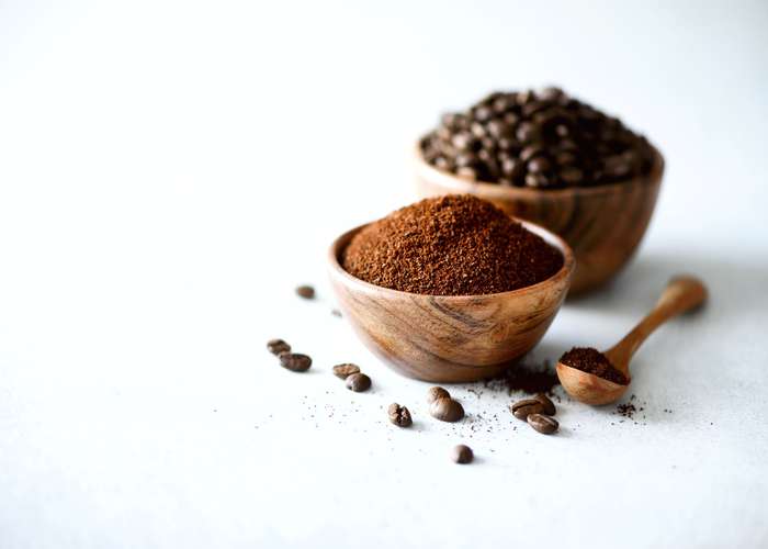 Avoid caffeine for ADHD: cups filled with coffee grains and grinded coffee, with a spoon on the side.