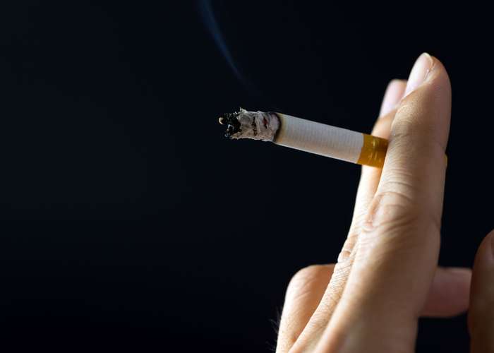 Avoid smoking for Alzheimer: close up on a woman's hand, smoking cigarette.