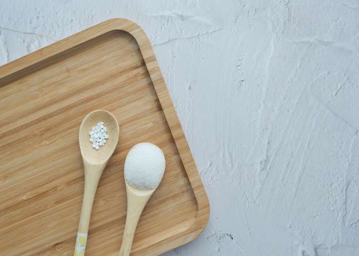 Avoid sweeteners for IBS: sweetener next to a spoon full of sugar.