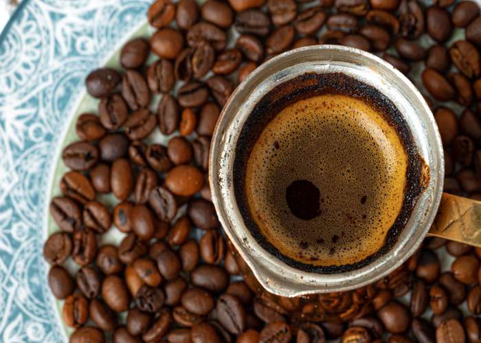 Avoid coffee for IBS: steel coffee boiler and next to it coffee grains.