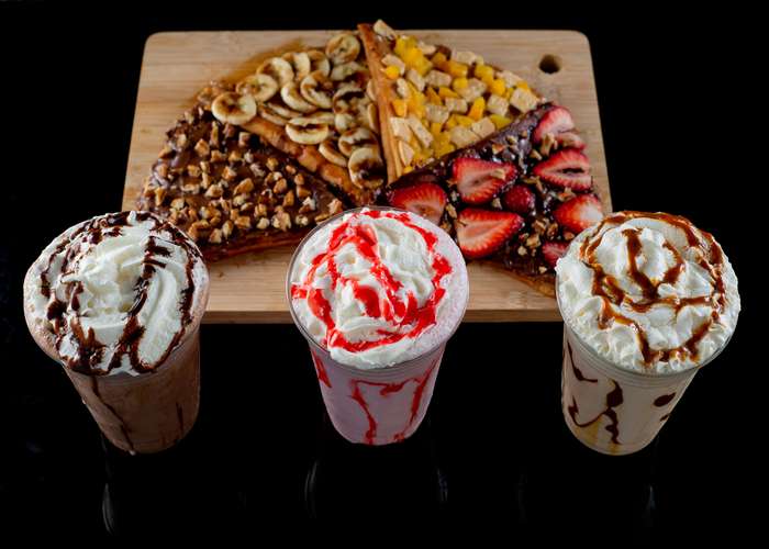 Avoid fatty and sugary foods for liver disease: milk shakes and sweet crepes on a wooden plateau.